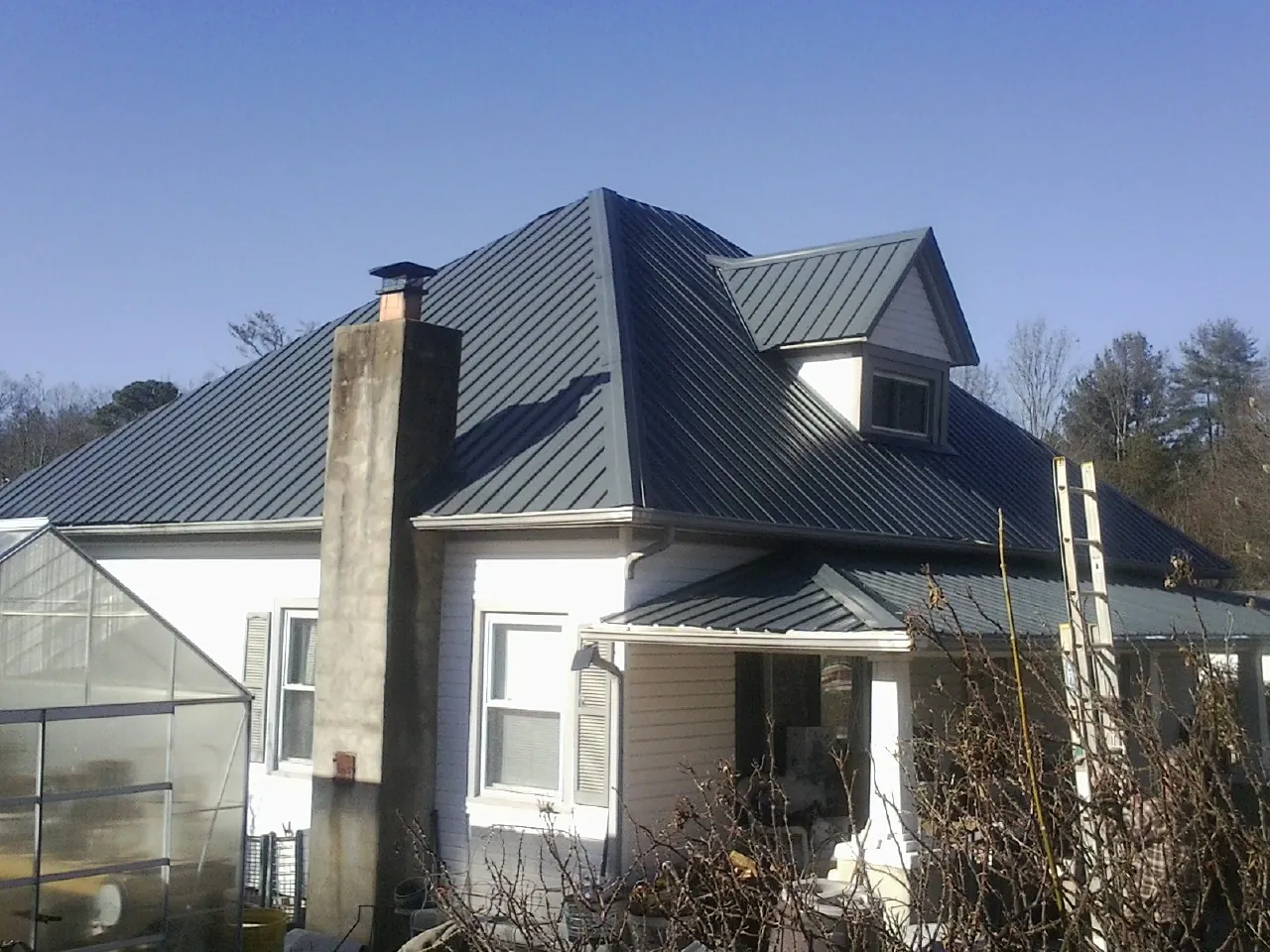 Dark blue standing seam metal roof on a white farmhouse with dormer — Slate & Tile Roof Repair by Roofing Brothers in Plainsboro