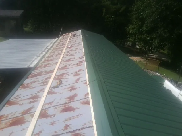 Old rusted panels beside newly installed green metal roofing — Wind Damage Roof Repair by Roofing Brothers in Plainsboro