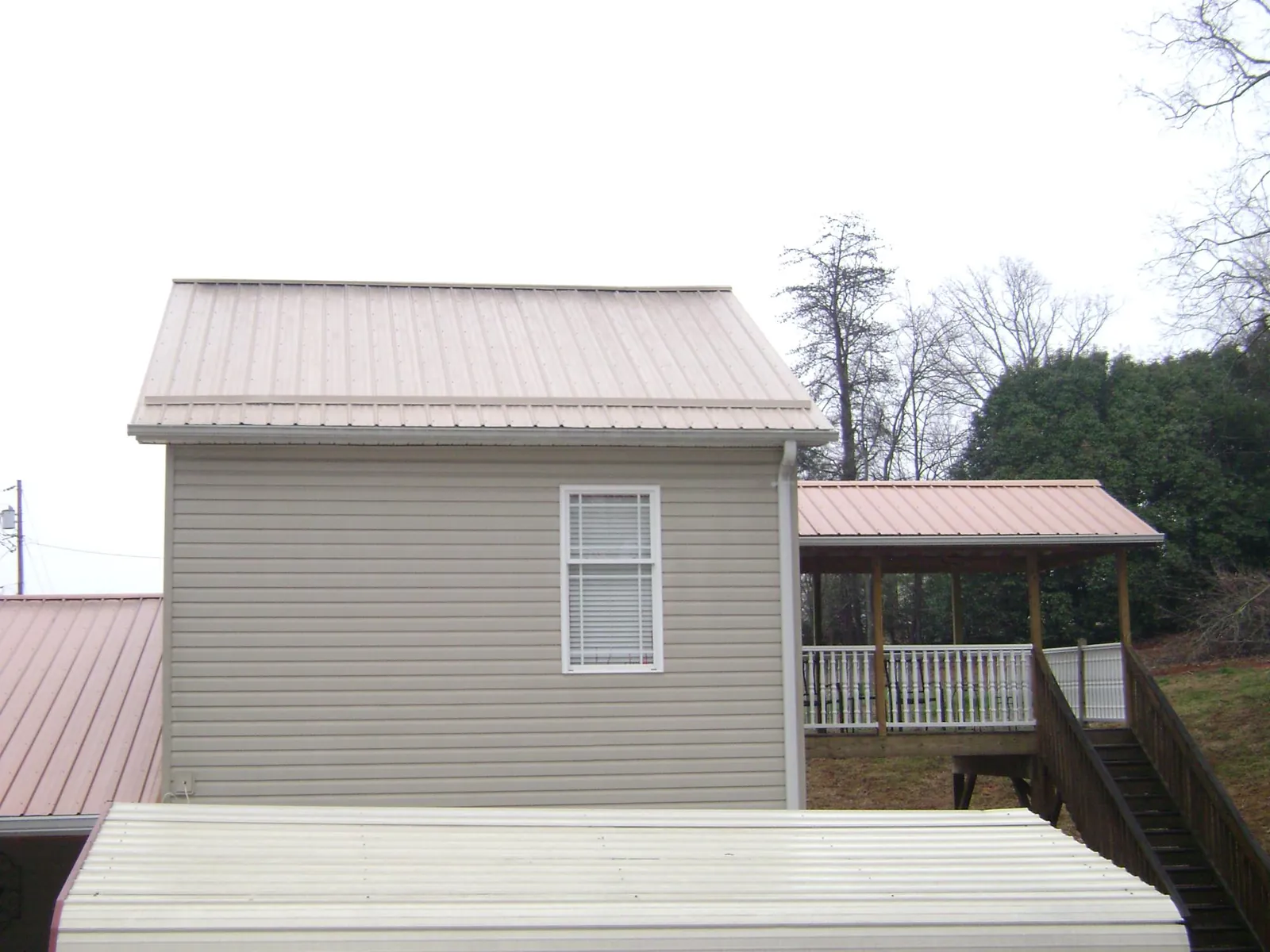 Tan metal roofs on a two story addition and attached porch, from a Roof Replacement job in Plainsboro