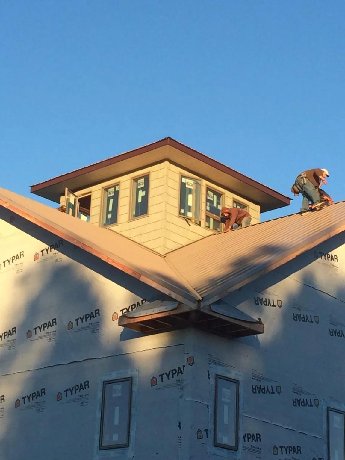 Roofers working around a rooftop cupola on a new metal roof at sunset — Roof Waterproofing in Plainsboro by Roofing Brothers